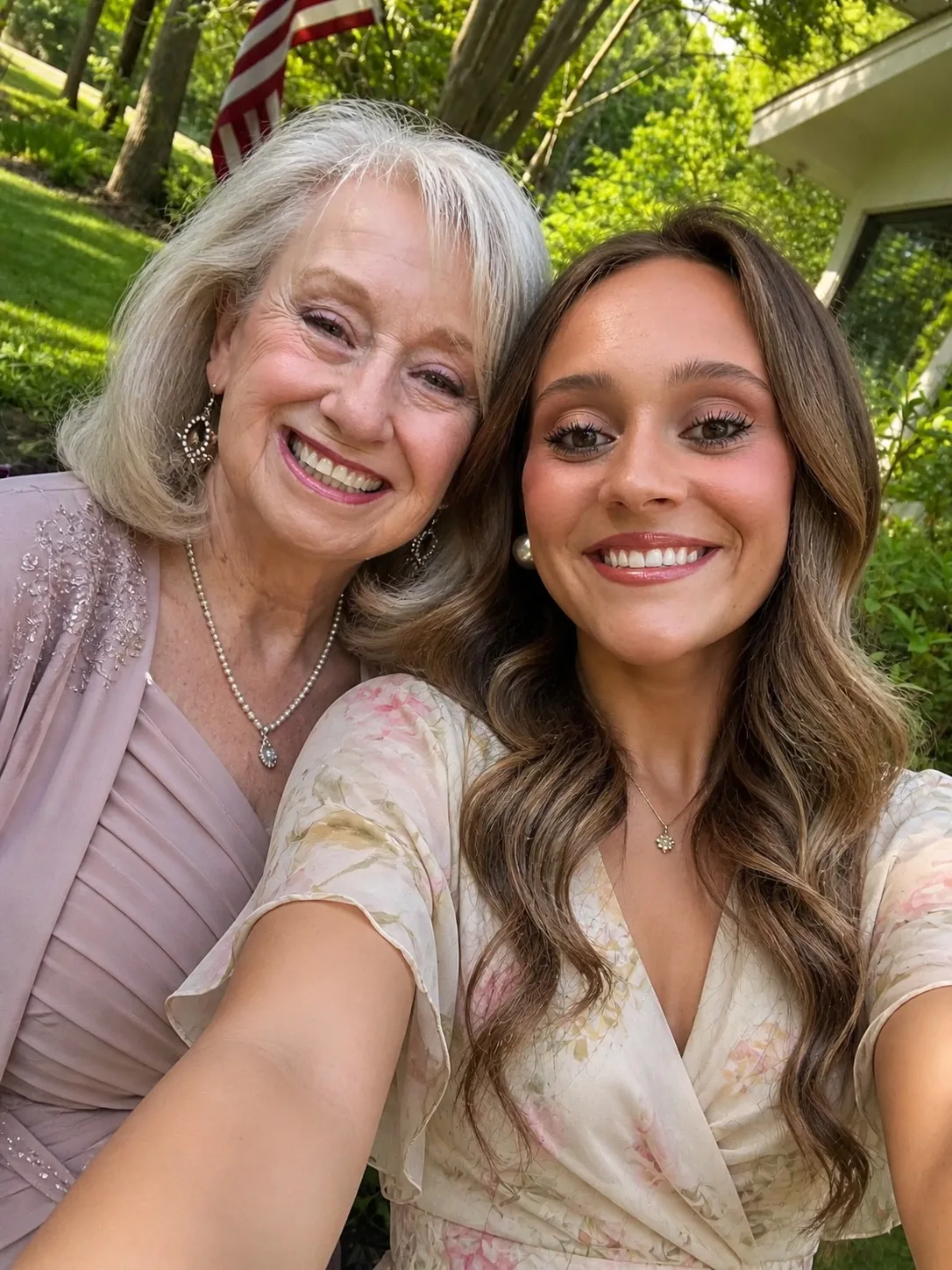 Brenda and a younger woman smiling together outdoors in soft formal clothes