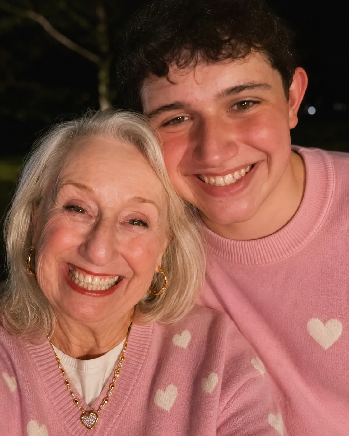 Brenda and a young man smiling in matching pink sweaters with heart details