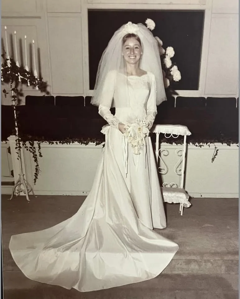 A young Brenda standing in a long wedding dress and veil in a black-and-white bridal portrait
